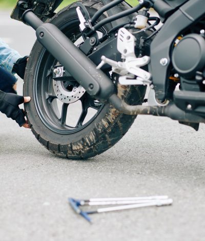 Close-up image of man replacing damaged tire of motorcycle